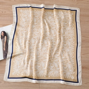 Macro view of silky paisley square scarf with navy borders on a wooden table