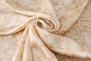 Macro detail of champagne gold satin scarf featuring intricate white paisley patterns