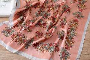 Detail eines Seidenschals mit Korallenblumenmuster und feiner Textur auf Satin-Stoff