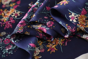 Makro-Detail des dunkelblauen Seidenschals mit Blumenmuster und feinem Seidenglanz