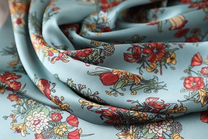 Detaillierte Makroansicht des grau-blauen Satin-Seidenschals mit elegantem Blumenmuster