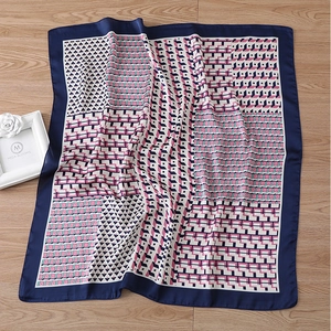 Detailed flat lay of geometric silk scarf with navy borders on a wooden background