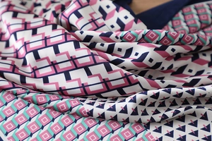 Close-up of geometric silk scarf with pink and navy patterns and premium satin texture