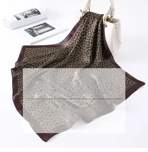 Foulard carré en soie imprimé léopard noué sur un sac à main blanc élégant