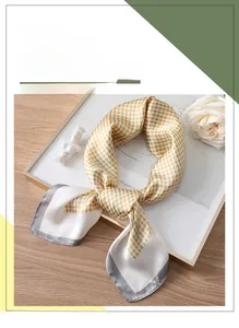 Detailed view of yellow houndstooth silk scarf with dark grey borders on a clean surface