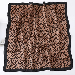 Détail d'un foulard carré en satin léopard avec bordure noire et texture soyeuse