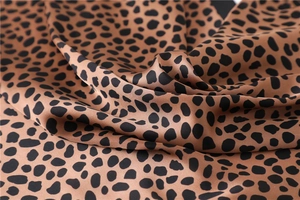 Gros plan sur tissu satiné léopard montrant une texture lisse et des plis élégants