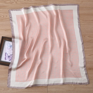 Detail of pink houndstooth square silk scarf with purple border on light wood background