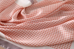 Detailed close-up of pink houndstooth silk scarf showing premium fabric texture and purple hem