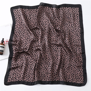 Détail macro du foulard en soie à imprimé léopard avec bordure noire sur fond blanc