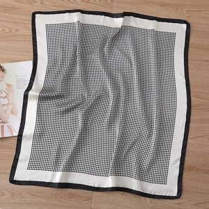 Detailed view of black and white houndstooth silk scarf on wooden background with magazine