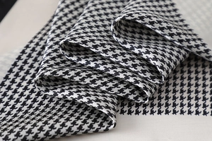 Macro detail of high-quality houndstooth satin silk scarf showing soft texture and sheen
