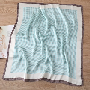 Detail of light blue houndstooth silk scarf with purple borders on a wooden surface