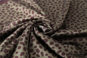 Vue macro de la texture d'un foulard en soie léopard avec des plis en satin vert olive