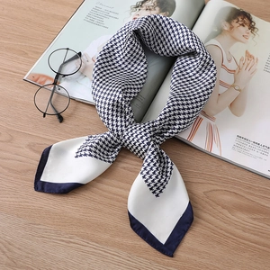 Close-up of a tied houndstooth silk scarf in navy and white on a wooden background