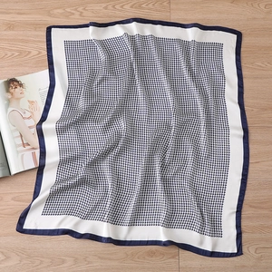 Detail of classic houndstooth silk scarf on wood with blue rolled hem edge
