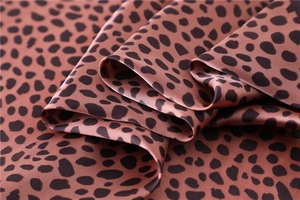 Vue détaillée du tissu satiné à imprimé léopard avec un fini soyeux et brillant luxe