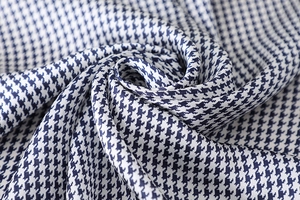 Macro detail of glossy blue and white houndstooth pattern on satin fabric texture