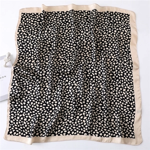 Gros plan d'un foulard carré en soie à imprimé léopard avec drapé élégant et pois