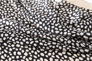 Vue détaillée de la texture soyeuse à pois avec un éclat satiné sur le tissu