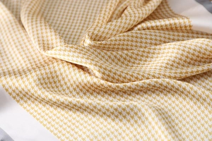 Macro shot of yellow and white houndstooth silk scarf with glossy texture and elegant folds