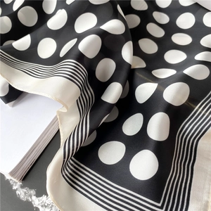 Détail d'un foulard en soie à pois noirs et blancs avec bordure rayée et éclat satiné