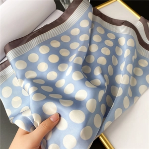 Détail d'un foulard en satin bleu clair avec pois blancs et bordure rayée élégante