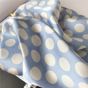 Gros plan du foulard en soie bleu clair à pois blancs avec texture satinée