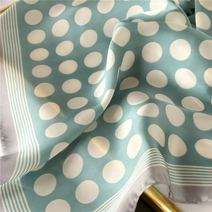 Gros plan d'un foulard en soie vert clair à pois avec bordure rayée élégante