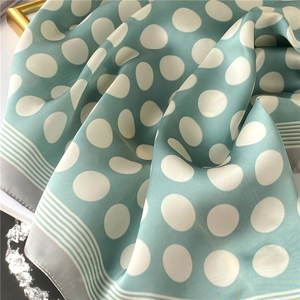 Détail d'un foulard en soie vert menthe à pois avec bords rayés et éclat satiné