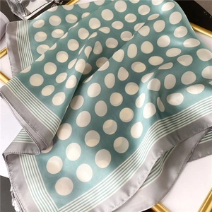 Détail d'un foulard en soie à pois bleu sarcelle avec bordures élégantes à rayures grises