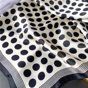 Détail d'un foulard en soie à pois avec bords rayés et texture satinée lisse