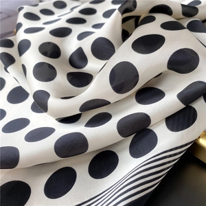 Détail du foulard en soie blanche à pois noirs et bordure rayée montrant la texture douce