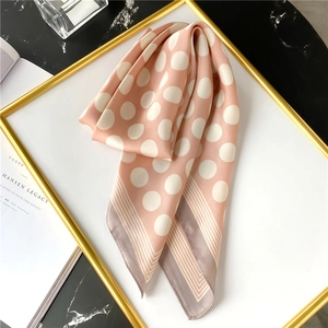Détail d'un foulard en soie rose à pois avec bords rayés sur fond de marbre