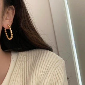 Détail macro de boucles d'oreilles créoles dorées à perles sur mannequin élégant