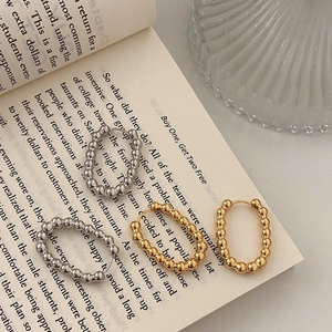 Vue détaillée des boucles d'oreilles ovales perlées dorées et argentées sur un livre