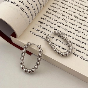 Vue détaillée de boucles d'oreilles créoles perlées argentées sur une page de livre