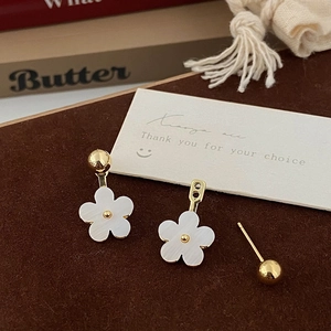 Detail of French floral earrings with white petals and gold core on soft velvet