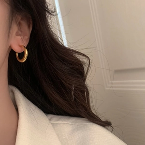 Gros plan de boucles d'oreilles créoles dorées et polies portées par un mannequin