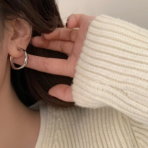 Gros plan de boucles d'oreilles créoles argentées minimalistes portées par un mannequin