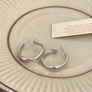 Détail de boucles d'oreilles géométriques en C argentées avec texture effet liquide