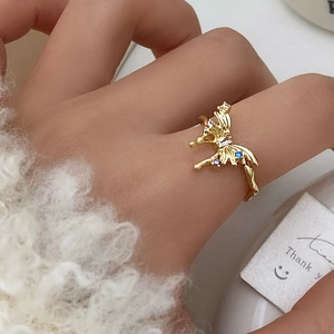 Gros plan détaillé d'une bague papillon dorée avec cristaux colorés sur une main