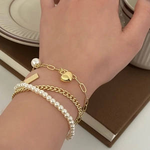 Close-up of pearl and gold heart bracelet set worn against a vintage background