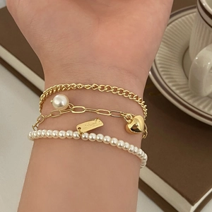 Elegant gold layering bracelet set with pearls, heart charm and handmade tag on wrist