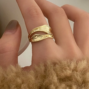 Close-up of a wavy hollow golden ring with artistic double-layer texture on a hand
