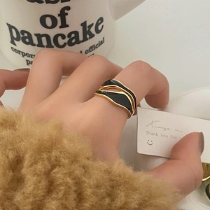 Close-up of a minimalist wavy ring with black enamel and gold plating on a model