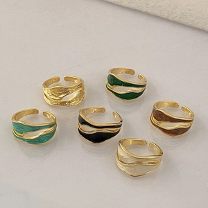 Close-up of wavy double-layered rings in gold finish with colorful enamel textures