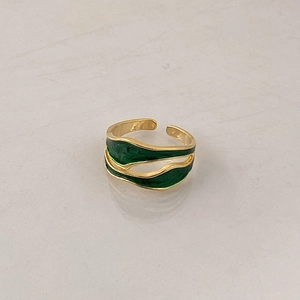 Detail of vintage gold wave ring with emerald green enamel inlay and open band