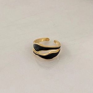 Detailed view of wavy gold open ring with black enamel inlay in minimalist style