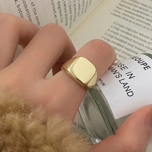 Close-up of a minimalist gold signet ring for men on a cozy lifestyle background